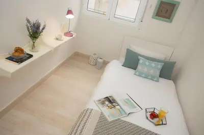 a small white room with a bed and a window at SingularStays Calderon in Valencia