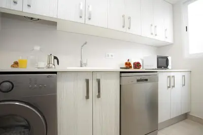 a kitchen with white cabinets and a washer and dryer at SingularStays Calderon in Valencia