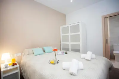 a white bedroom with a large bed with a vase on it at SingularStays Salvador II in Valencia