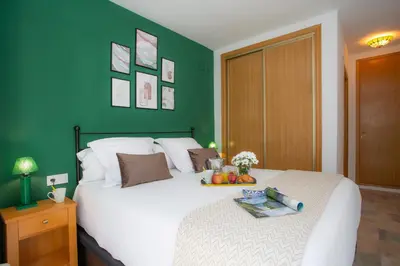 a bedroom with a white bed with a green wall at SingularStays Clero in Valencia