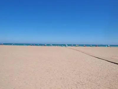 a sandy beach with umbrellas and the ocean at Apartamentos Las Ciencias U in Valencia