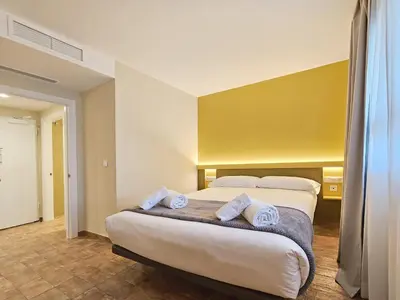 a hotel room with two beds and a yellow wall at Apartamentos Las Ciencias V in Valencia