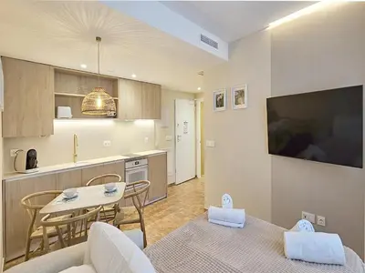 a kitchen and a living room with a table and a tv at Apartamentos Las Ciencias V in Valencia