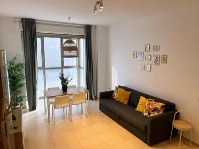 a living room with a black couch and a table at Valencia Beach Apartment - La Patacona in Valencia