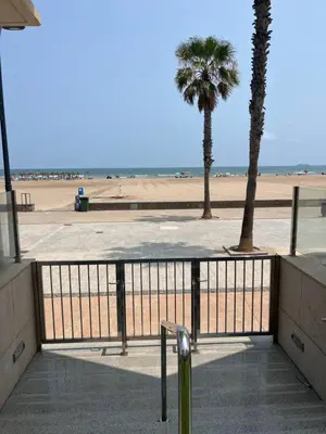 a view of a beach with a fence and palm trees at Valencia Beach Apartment - La Patacona in Valencia