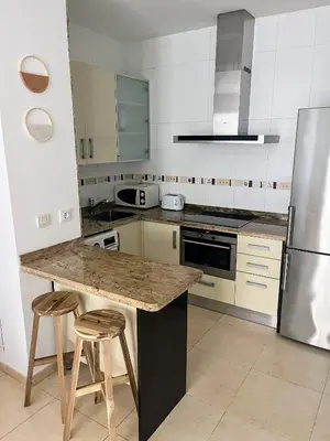 a kitchen with a counter with stools and a refrigerator at Valencia Beach Apartment - La Patacona in Valencia