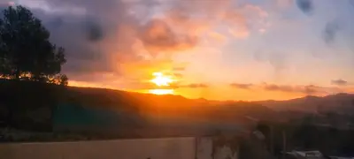 a sunset with the sun setting over a mountain at Alto Oasis in Siete Aguas