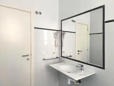 a white bathroom with a sink and a mirror at Flats Friends Torres Quart in Valencia