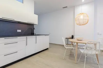 a kitchen with white cabinets and a table and chairs at Ca Celieta Beach I in Valencia