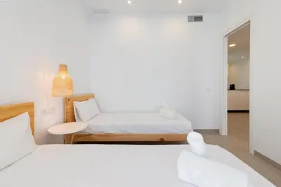 a white bedroom with two beds and a table at Ca Celieta Beach II in Valencia