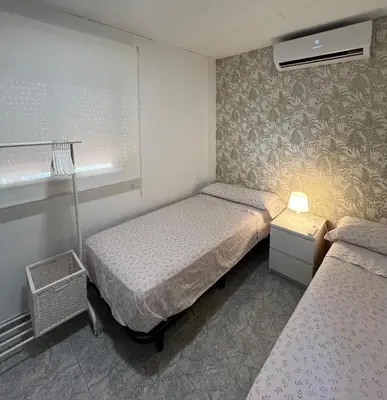 a small bedroom with two beds and a window at Casa Pagan in Cullera