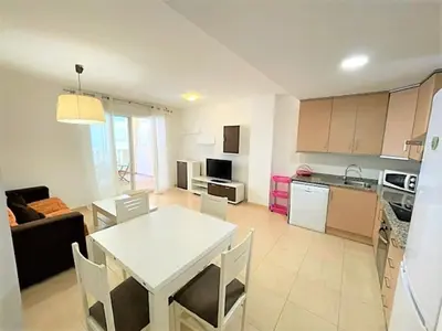 a living room with a white table and a kitchen at Apartment Grao de Moncofar Ref 041 in Moncófar