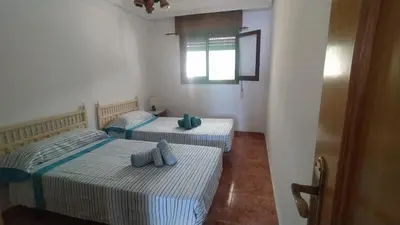 two twin beds in a room with a window at Apartamento Playero in Tavernes de Valldigna