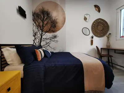 a bedroom with a bed with blue sheets and a tree on the wall at Portrait Boutique Apartment in Valencia