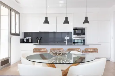 a white kitchen with a glass table and chairs at ApartUP Patacona Deluxe in Valencia