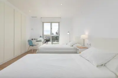 a white bedroom with two beds and a desk at ApartUP Patacona Deluxe in Valencia