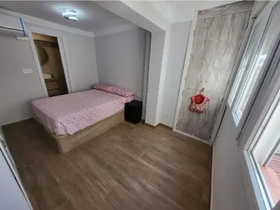 a small bedroom with a bed and a wooden floor at Playa y cultura en el Cabanyal Alquiler de temporada familiar in Valencia