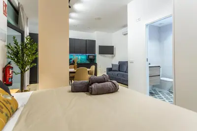 a bedroom with a large bed and a living room at Suite Deluxe Valencia - AIORA Apartments in Valencia
