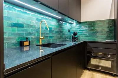 a kitchen with a sink and a blue tiled wall at Suite Deluxe Valencia - AIORA Apartments in Valencia