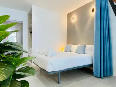 a bedroom with a white bed with blue curtains at Modern Designed Loft in Russafa (SOHO) in Valencia
