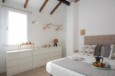 a white bedroom with a bed with a bowl of fruit on it at SingularStays Vivons in Valencia