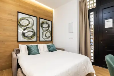 a bedroom with a white bed with three paintings on the wall at Anelsa Torres de Serranos 3 in Valencia