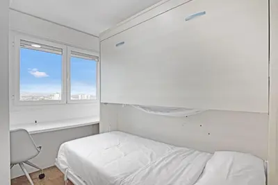 a white bedroom with a bed and a window at Apartamento atardecer dorado in Valencia