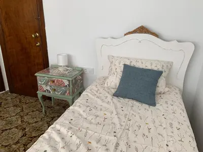 a bed with a blue pillow and a side table at Sagunto 2 in Sagunto