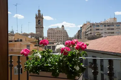 a pot of flowers on a balcony with a clock tower at Tossal in Valencia