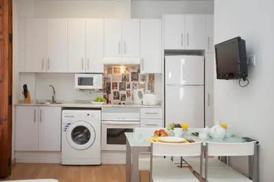 a kitchen with white cabinets and a table with a dishwasher at Tossal in Valencia