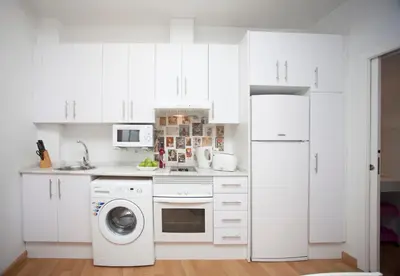 a kitchen with white cabinets and a washer and dryer at Tossal in Valencia