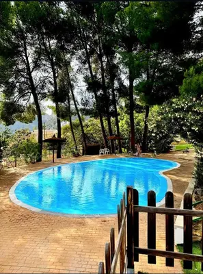 a blue swimming pool with trees in the background at La Casucha de Chulilla in Chulilla