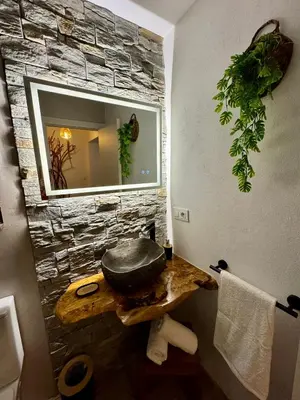 a bathroom with a stone wall and a mirror at La Casucha de Chulilla in Chulilla
