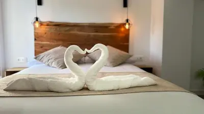 two white swans making a heart shape on a bed at La Casucha de Chulilla in Chulilla
