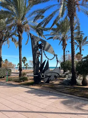 a large metal sculpture sitting between palm trees at Wohnung in Chilches in Xilxes