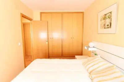a bedroom with a white bed and a closet at Ático con piscina en excelente urbanización by Hometels in Canet de Berenguer