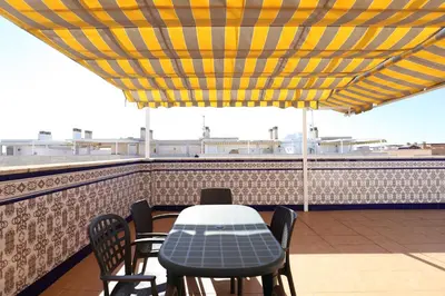 a table and chairs under a yellow and yellow umbrella on a roof at Ático con piscina en excelente urbanización by Hometels in Canet de Berenguer