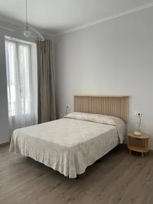 a bedroom with a large bed and two windows at Maison Sereine in Valencia