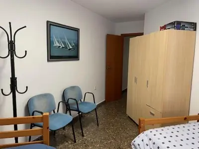 a bedroom with three chairs and a bed and a cabinet at Apartamento Diagonal in Nules