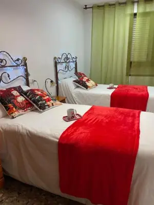 a bedroom with two beds with red and white sheets at Apartamento Diagonal in Nules