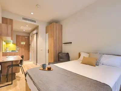 a bedroom with a large bed and a desk at Livensa Living Studios Valencia Viveros Hotel - Apartamento in Valencia