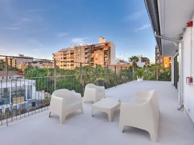 a balcony with white chairs and tables on a building at Livensa Living Studios Valencia Viveros Hotel - Apartamento in Valencia
