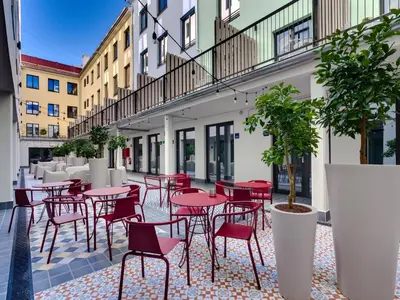 a patio with red tables and chairs in a courtyard at Livensa Living Studios Valencia Viveros Hotel - Apartamento in Valencia