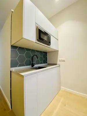a kitchen with white cabinets and a microwave at FLORIT FLATS - The Cabanyal & Port Suites in Valencia