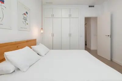 a white bedroom with a large bed with white pillows at ApartUP Valencia Opera in Valencia