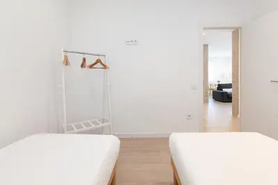 two beds in a room with white walls and wooden floors at ApartUP Valencia Opera in Valencia