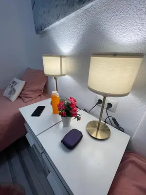 a bed with a table with a lamp and flowers on it at Piso tranquilo y luminoso en Valencia in Valencia