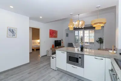 a kitchen with white cabinets and a living room at GuestReady - El Cabanyal Hidden Oasis in Valencia