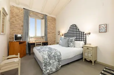 a bedroom with a large bed with a black and white headboard at Maison Muralleta B&B in Riba-Roja De Turia