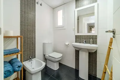 a white bathroom with a toilet and a sink at Ático Balinés con vistas al mar in Canet de Berenguer